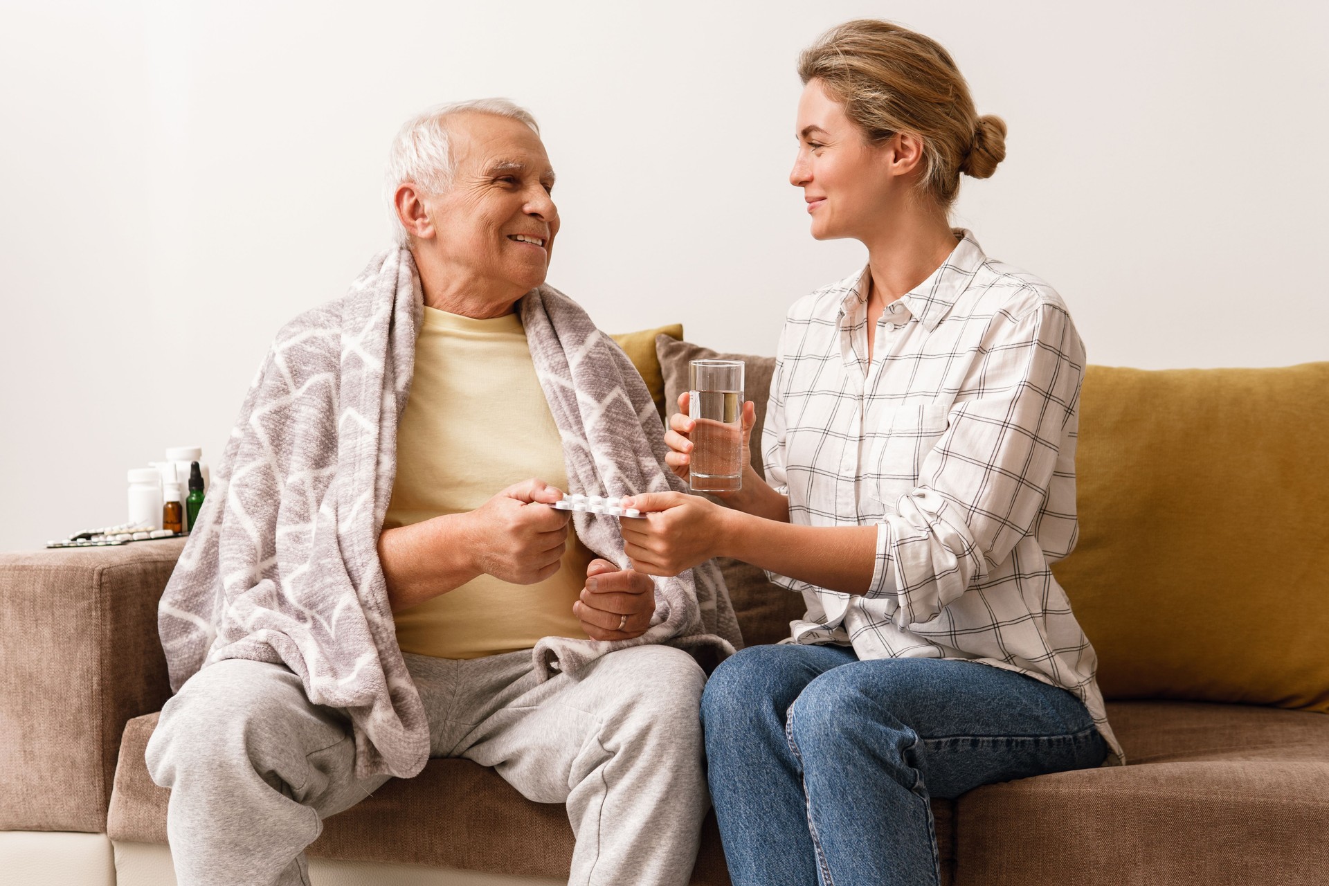 Woman is giving medicine to her sick elderly grandfather